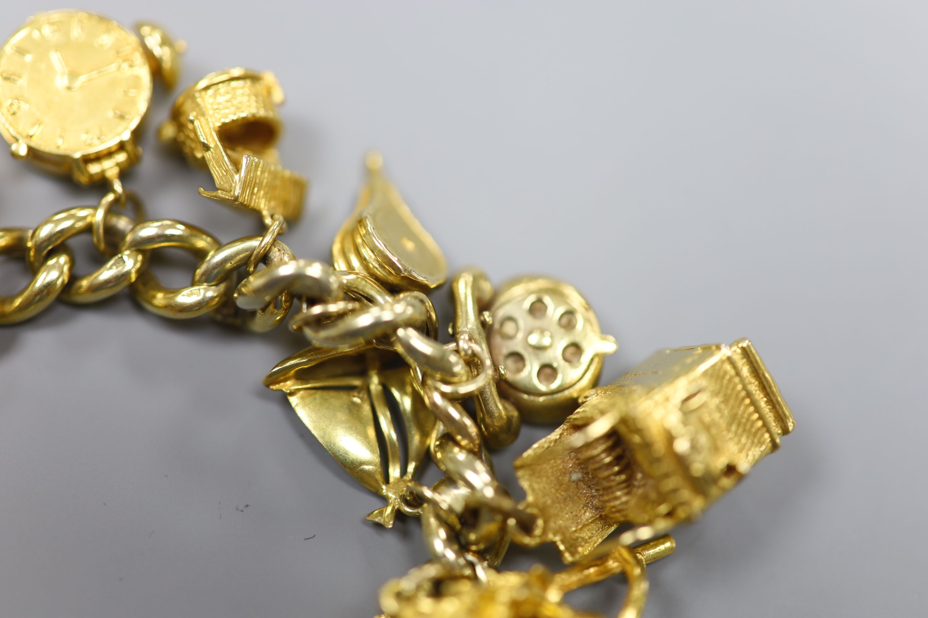 A 9ct curb link charm bracelet hung with twenty one assorted mainly 9ct gold charms